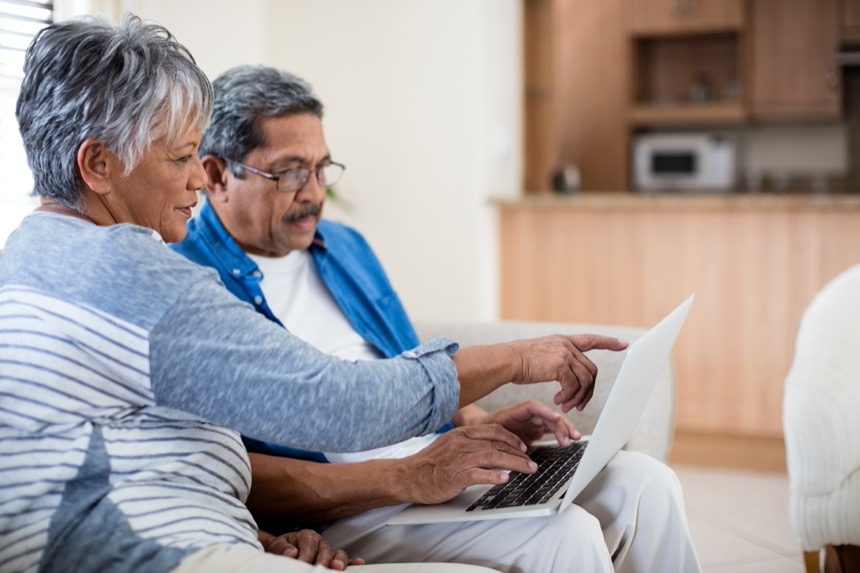 A couple sitting on the couch looking at a laptop